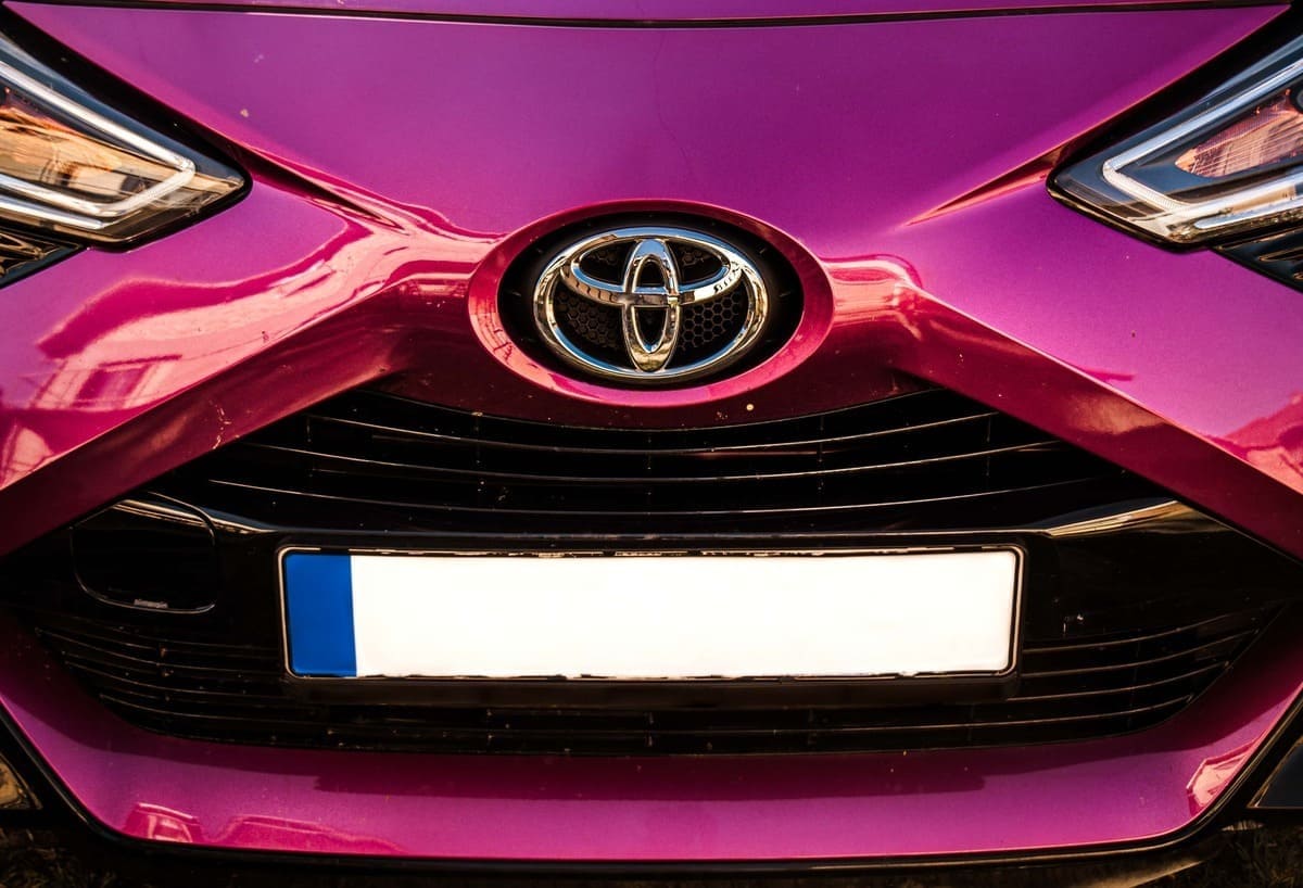Toyota - 2025 TOP - tumeroosa Toyota eestvaates, näha on logo, iluvõre ja osa esituledest