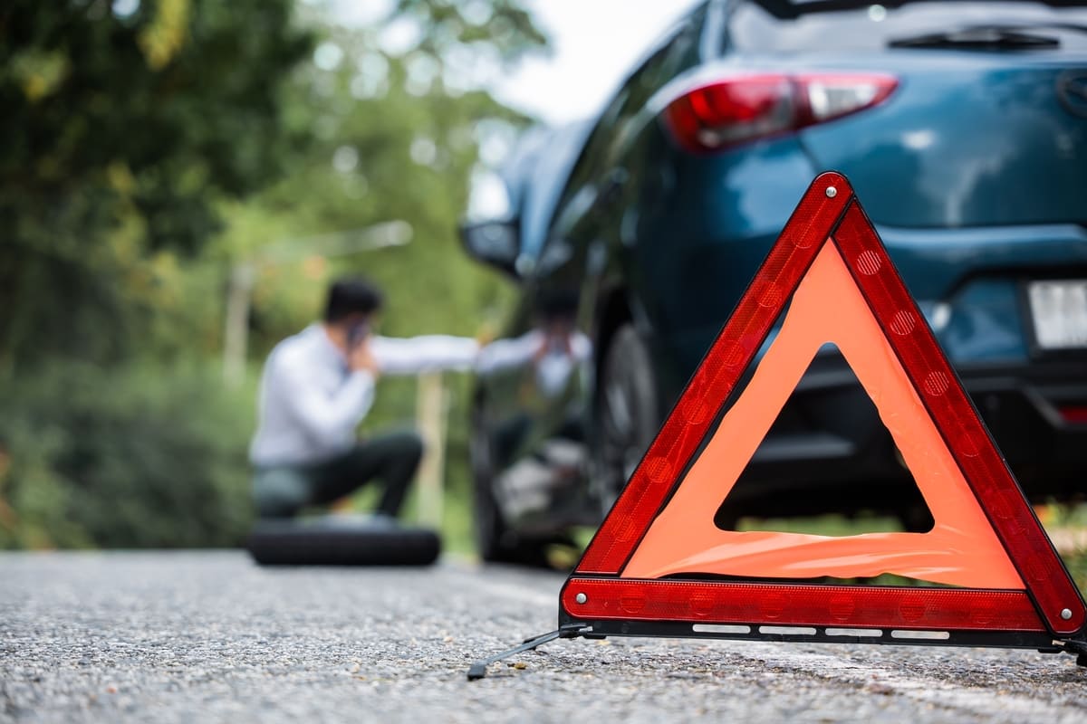Autoabi - ohukolmnurk ja mees musta auto juures helistamas