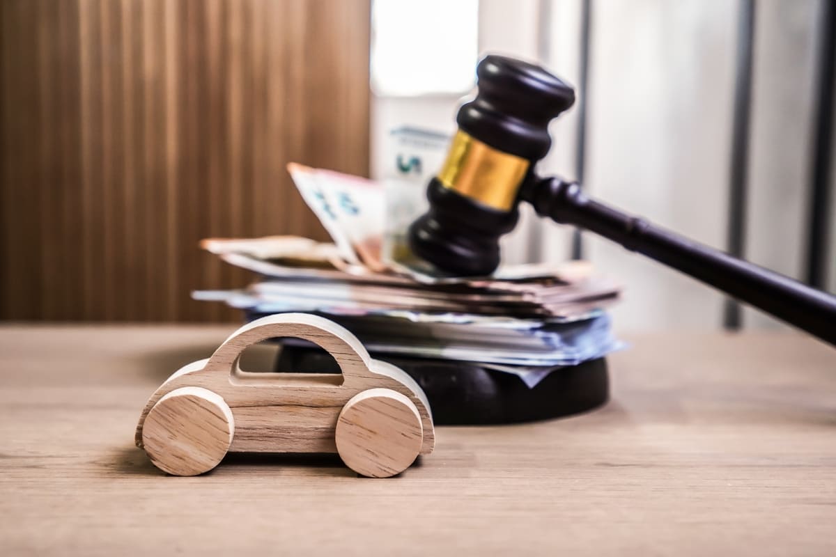 Automaatne liikluskindlustus - puidust mudelauto eurod paberkupüürides ja kohtuniku haamer