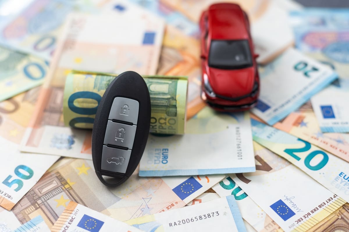 Liikluskindlustuse kaitse - punane mudelauto ja autovõtmed raharullile toetumas